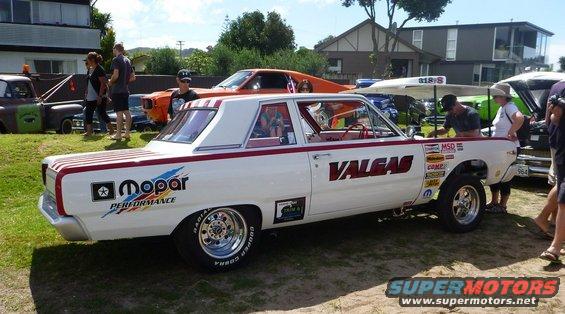 White Dodge Dart with red stripes and 'Valgas' text, drag racing slicks, and Mopar Performance decals