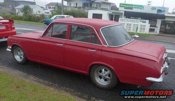 Red sedan with chrome trim and aftermarket wheels parked on a street