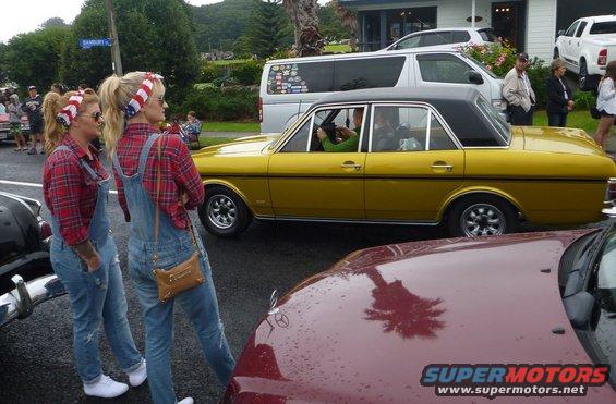 Yellow sedan with black vinyl roof and two women in overalls standing nearby