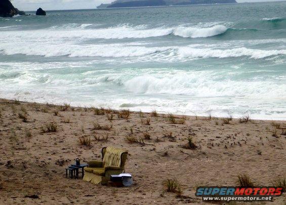 Armchair and side table on a sandy beach with ocean waves