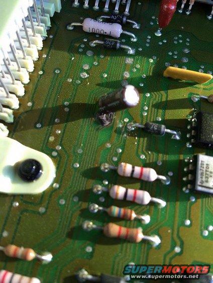 Close-up of a green circuit board showing various electronic components like resistors, capacitors, and integrated circuits