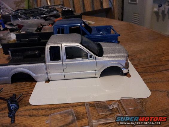 Silver pickup truck model in progress, with blue truck model behind it