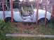 1991 Ford Bronco - An abandoned light blue SUV sits in tall grass, missing its doors and roof.
