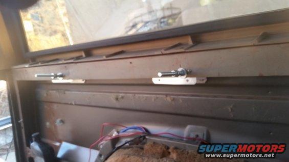 Interior view of a vehicle's rear cargo area with two mounting brackets and wiring