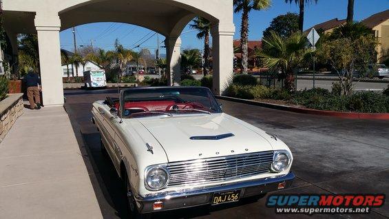 White 1963 Ford Falcon convertible with red interior parked under an archway