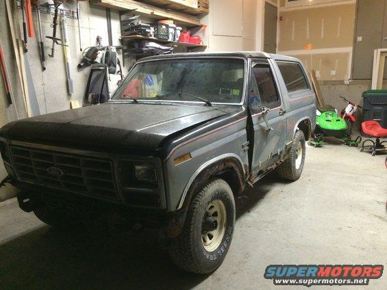 Gray 1986 Ford Bronco with front damage and missing door panel