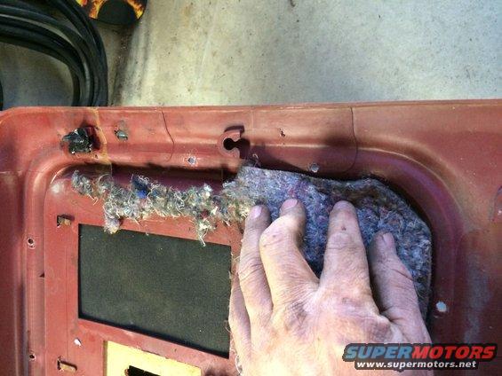 hand pulling insulation from red car door panel
