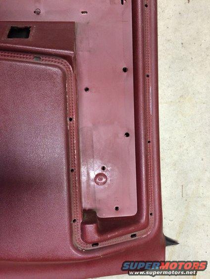 Maroon car door panel interior with visible mounting holes and textured trim