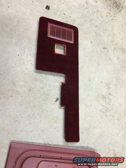Maroon car door panel with a vent and a square cutout, lying on a concrete floor