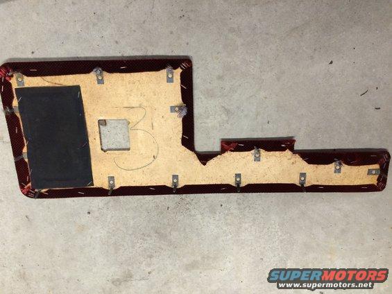 Car door panel with red fabric and exposed backing, showing metal clips and a square cutout