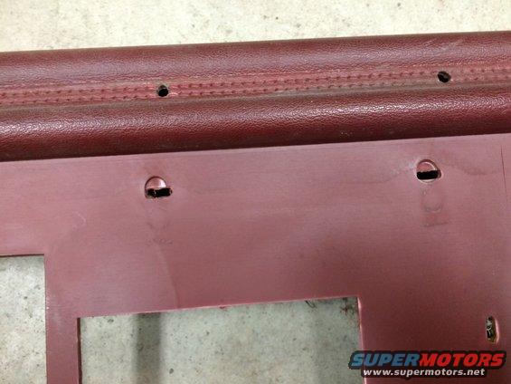 Close-up of a maroon car interior door panel with mounting holes