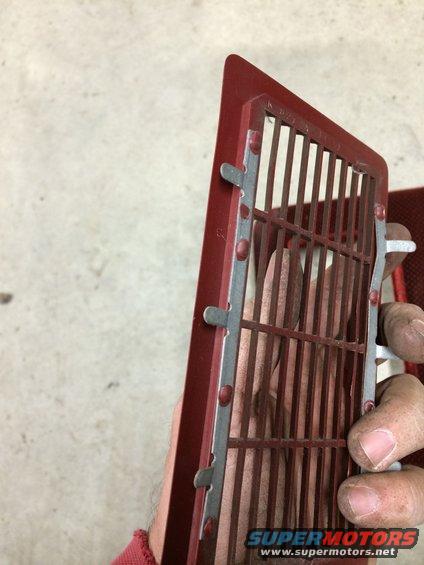 Red vent grille with metal bars held by a hand