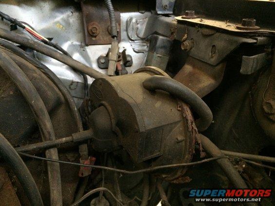 Close-up of dusty engine bay parts with hoses and wires