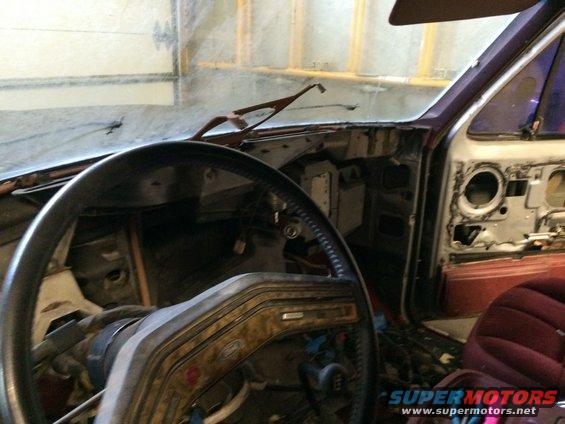 Interior of a vehicle with dashboard removed, showing steering wheel and door panel
