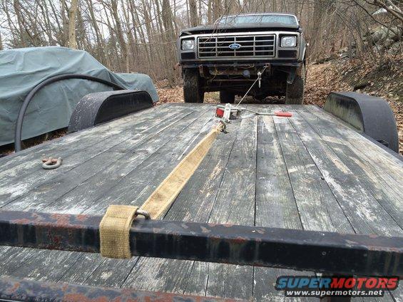 Ford truck being loaded onto a trailer. It has a prominent grille and Ford emblem