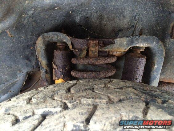 Heavily rusted suspension components above a worn tire