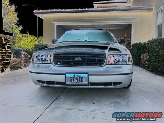 Front view of a silver Ford Crown Victoria with a black hood and grille. Iowa license plate reads 'ST VIC'