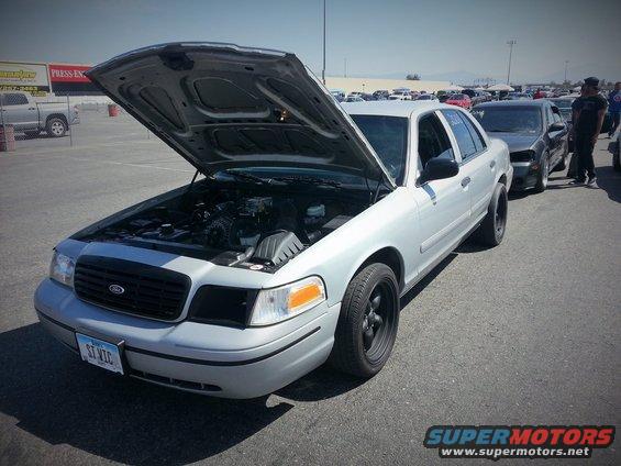 Silver 2003 Ford Crown Victoria with hood open, black wheels, parked in a lot