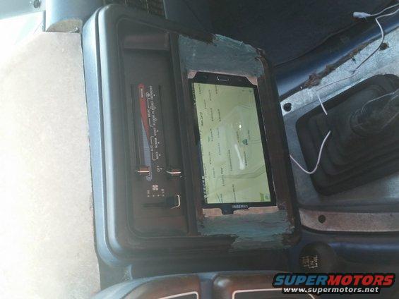 Dashboard interior with a tablet displaying a map mounted in a custom cutout, next to climate controls and a gear shifter