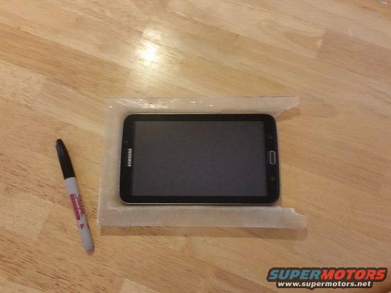 Samsung tablet on a wooden surface next to a marker