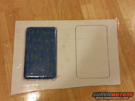 Blue object with green pattern next to a drawn rectangle on white paper