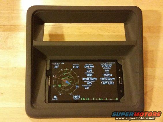 Dashboard mount holding a Samsung smartphone displaying GPS coordinates, heading, and speed