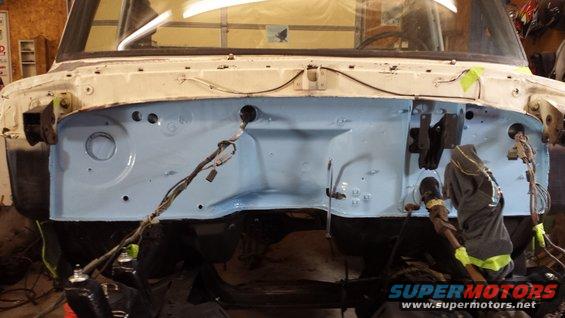 Engine bay firewall painted light blue with wiring harnesses