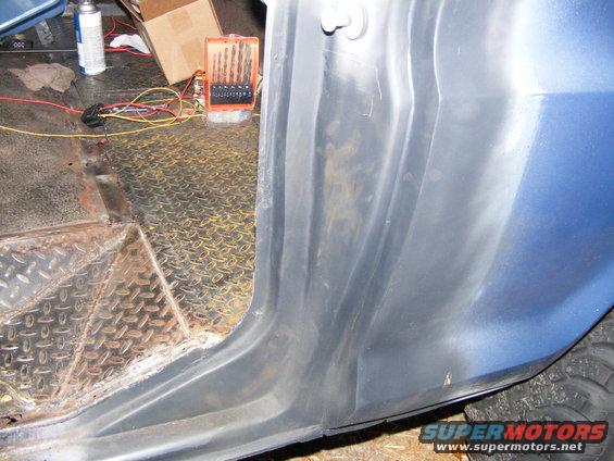 Close-up of a vehicle's interior door sill and diamond plate flooring, with tools and a spray can visible in the background