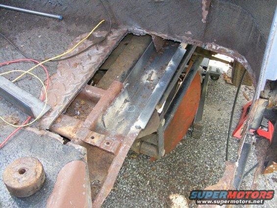 Rusted floor pan and frame with exposed metal and wiring