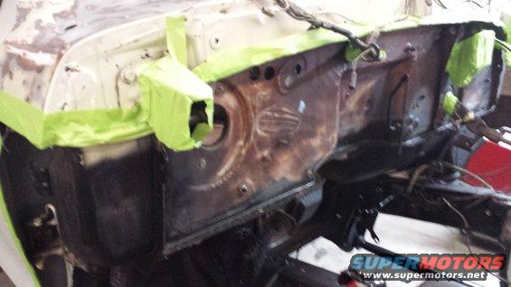 firewall area of a vehicle under repair, with green tape on the edges