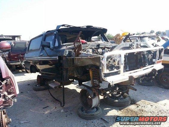 Junkyard Ford Bronco, front view, missing hood and grille, body damaged, wheels removed