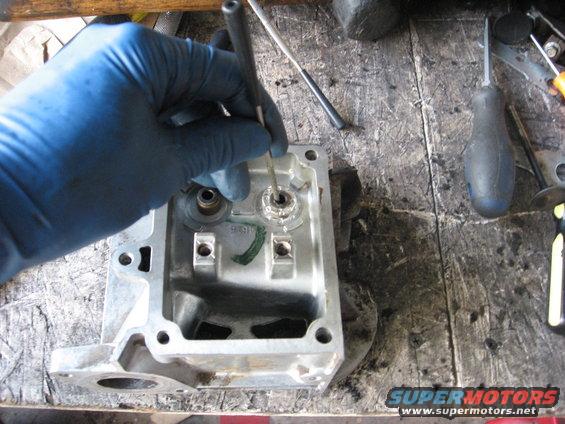 Gloved hand using a tool on an engine component on a workbench