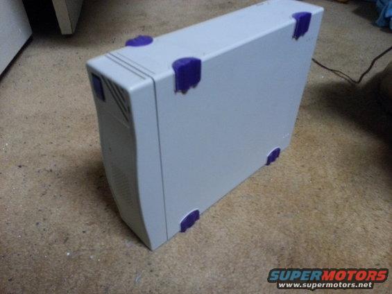 Gray computer tower with purple corner protectors on a carpeted floor