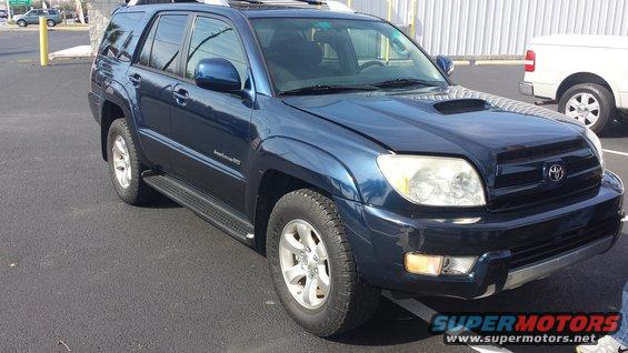 Blue Toyota 4Runner parked on asphalt, front 3/4 view. Hood is slightly ajar