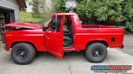red pickup truck with hood and driver door open, parked in driveway