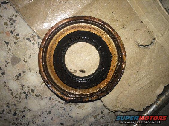 Close-up of a used oil seal with black rubber and a rusty metal casing