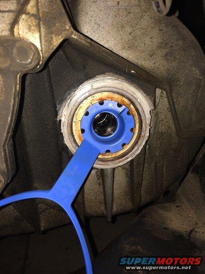 Blue tool inserted into a transmission housing to install a CV shaft seal
