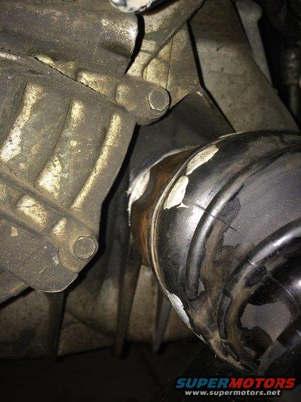 Close-up of a CV joint boot and part of a transmission housing. White sealant is visible on the boot