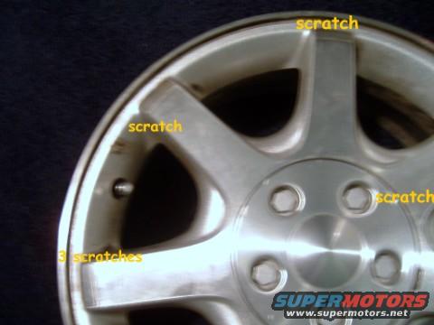 Close-up of a silver alloy wheel showing multiple scratches and the text '3 scratches'