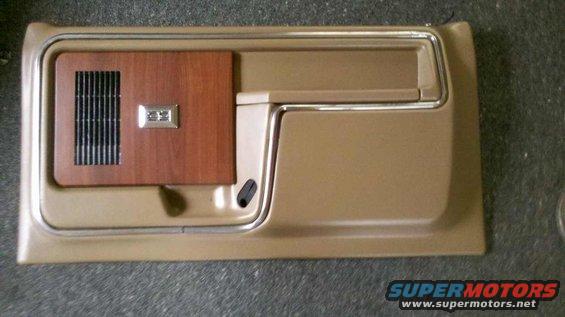 Tan door panel with wood grain insert, speaker grille, and chrome trim