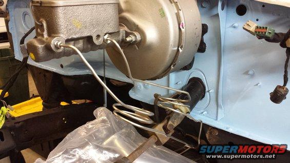 Brake booster and master cylinder assembly with metal brake lines coiled