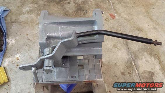 Gray metal part with black lever on a workbench