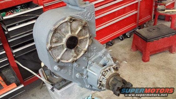 Gray transfer case with bolted housing and output shaft. Red tool chest in background