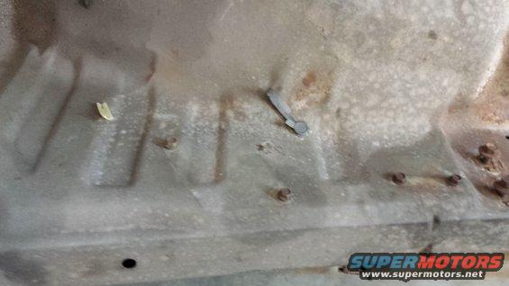 Underside of vehicle showing rust and a metal clip