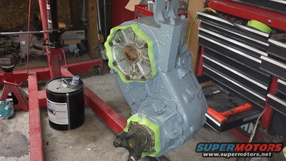 Gray painted transfer case on an engine stand, with green tape around input and output flanges