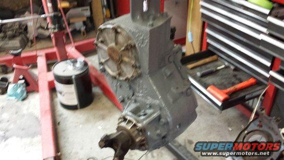 Gray transmission assembly on red engine hoist, with tools on a nearby cart