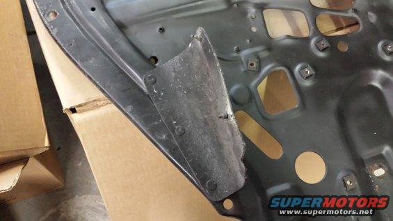 Underside of a car hood with some bracing and cutouts. Cardboard boxes are visible to the left