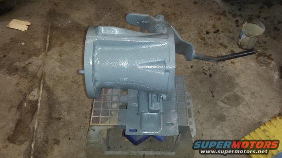 Gray painted transmission housing with a lever attached, resting on a blue and gray stand