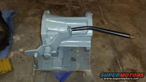 Gray painted metal part with a black lever, on a concrete floor