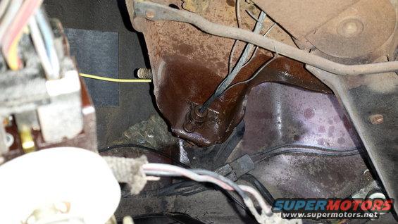 Engine bay with rusty metal, wires, and a yellow cable